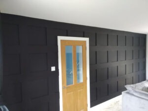 Dramatic dark grey panelled feature wall with oak door, finished