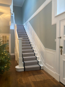 Restored period hallway and staircase with crisp white panelling and soft sage walls